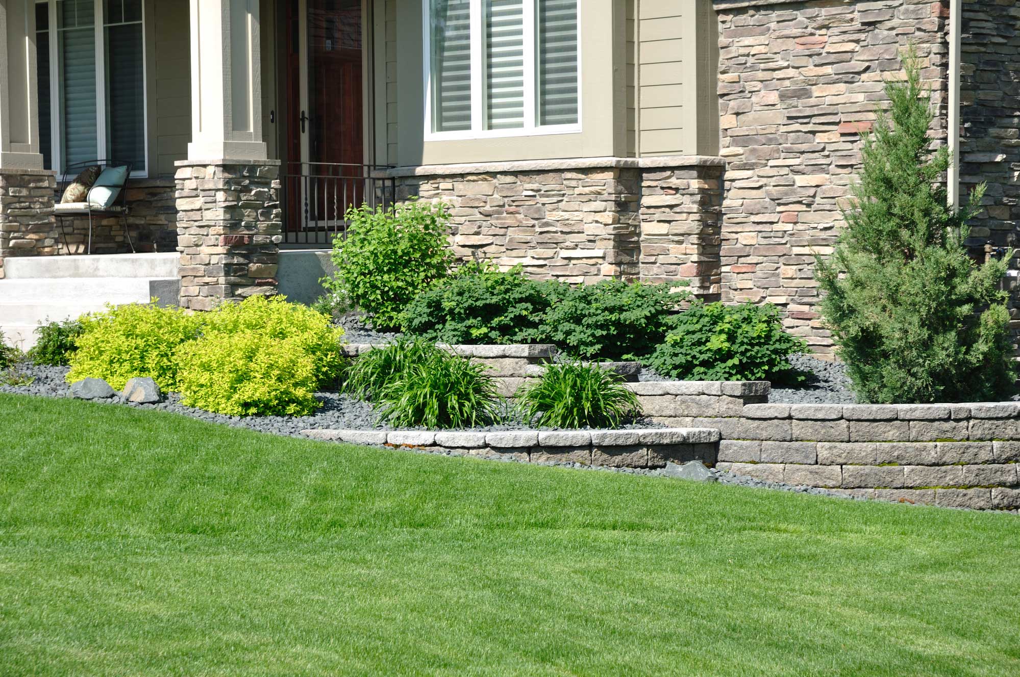 Yard with hardscape retaining wall for garden and gravel cover.